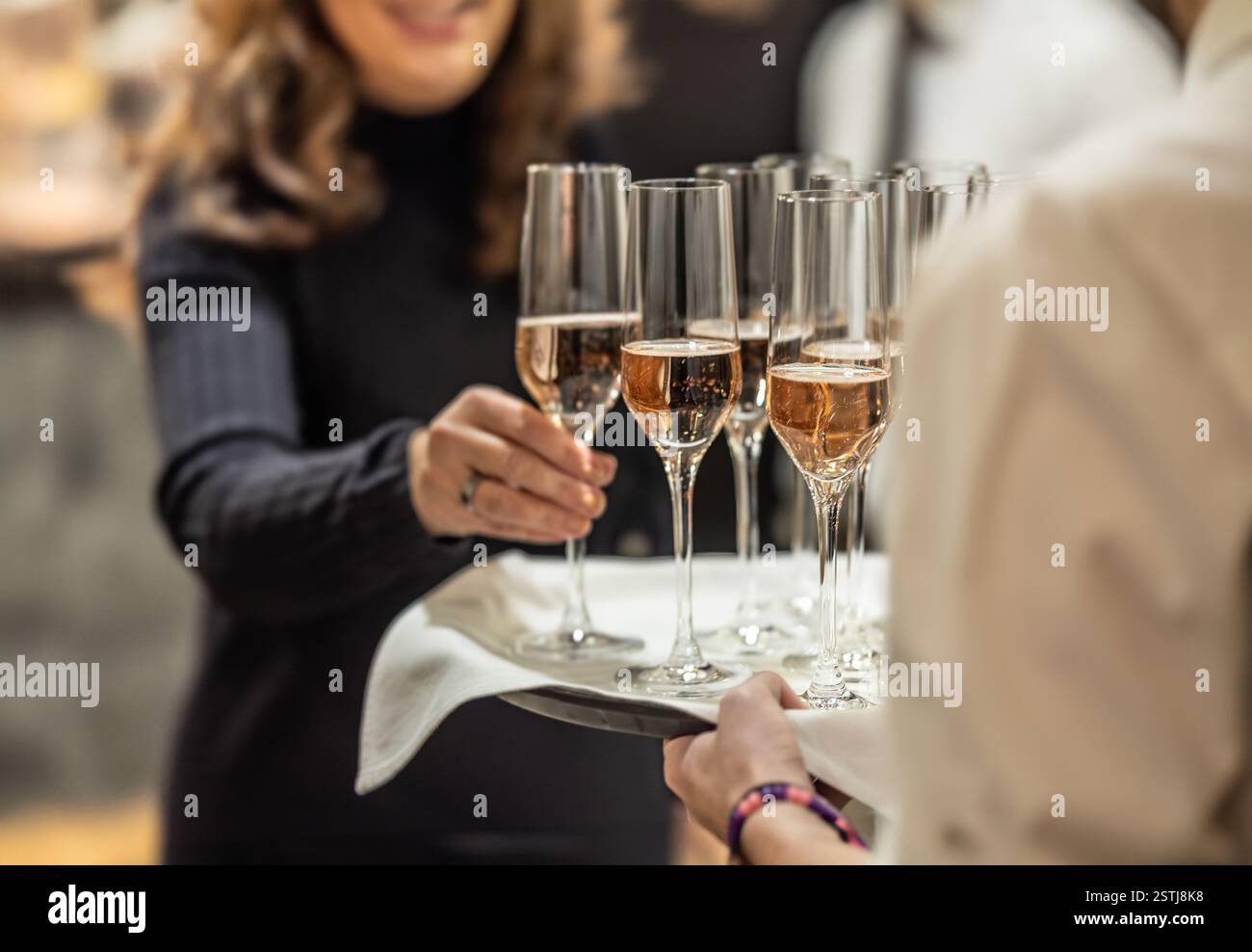 Young waiter holding a tray with champagne or prosecco at a wedding or gala event and offering guests a welcome drink Stock Photo