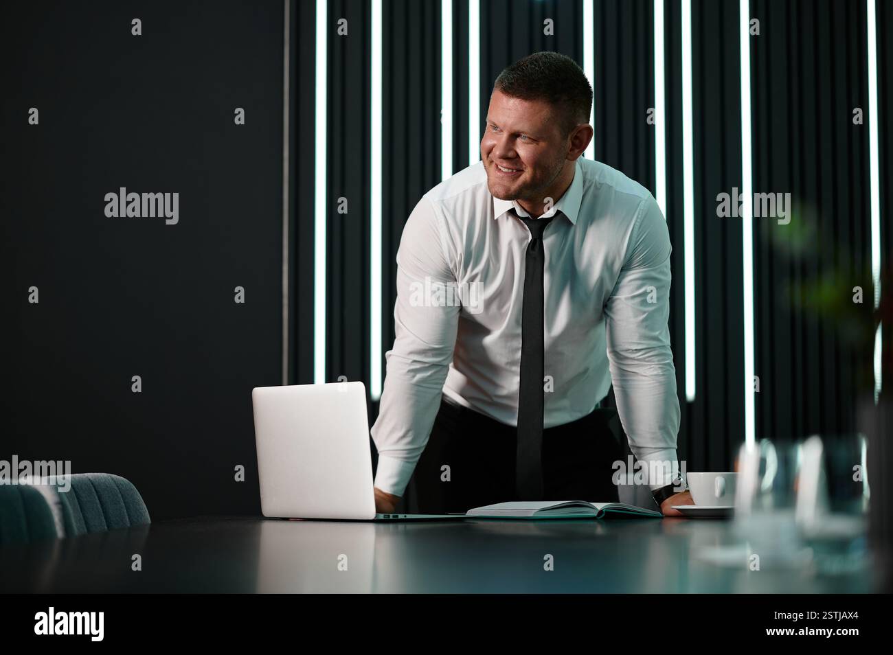 Architect looking at material samples while working on a project in office. Businessman standing at workstation in office. Medium wide shot portrait m Stock Photo