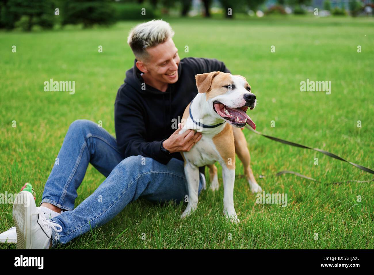 Picture of a young happy man walking his dog in a park , smiling guy ...