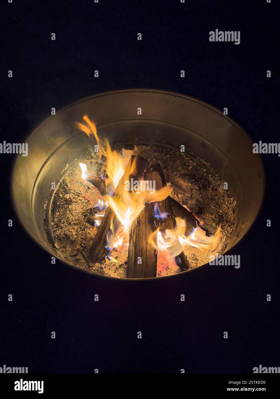 High angle view of campfire in metal fire pit at night Stock Photo