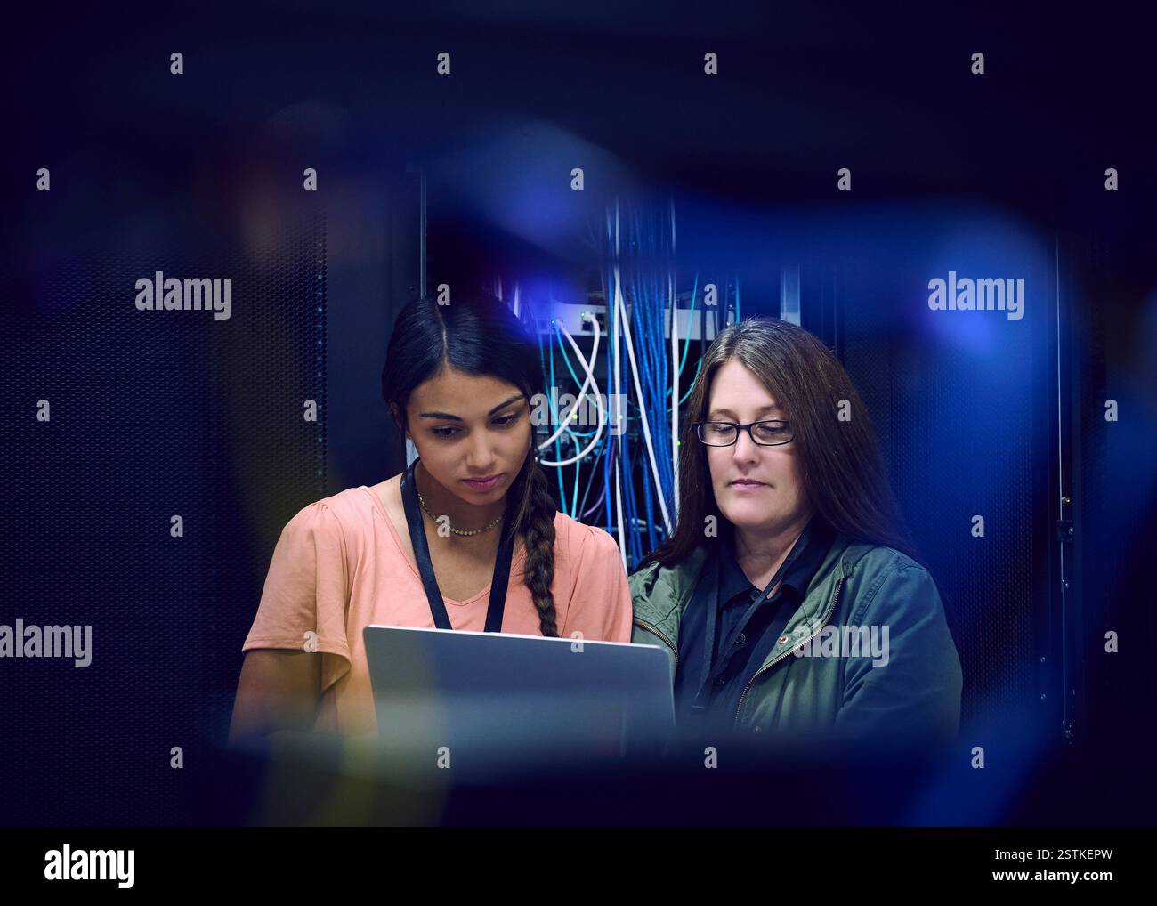 Two female technicians using laptop in server room Stock Photo