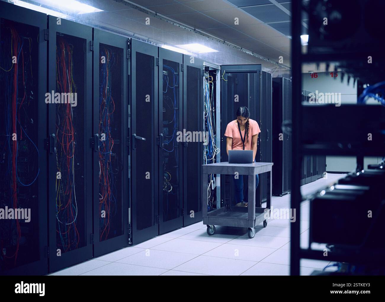 Female technician using laptop in server room Stock Photo