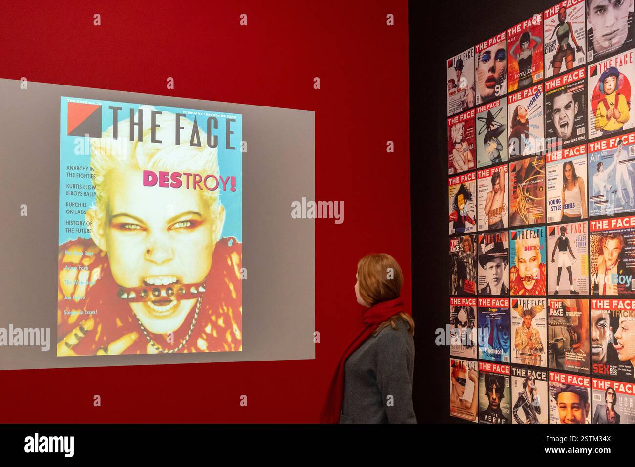 [Editorial Use Only – Critique or review only] London, UK.  19 February 2025. A staff member with a wall of front covers and digital projection at a preview of ‘The Face Magazine: Culture Shift’ at the National Portrait Gallery.  The exhibition celebrates images from The Face, the youth culture and style magazine which ran from 1980 to 2004, that has shaped the creative and cultural landscape in Britain and beyond.  The show runs 20 February to 18 May 2025. Credit: Stephen Chung / Alamy Live News Stock Photo