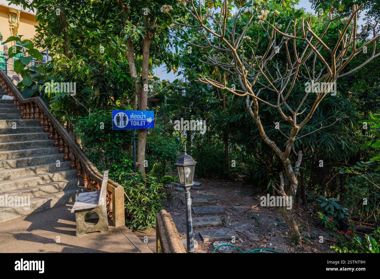 Concrete stairway with wooden railing and blue toilet directional sign at Kao Hua Jook Pagoda Stock Photo