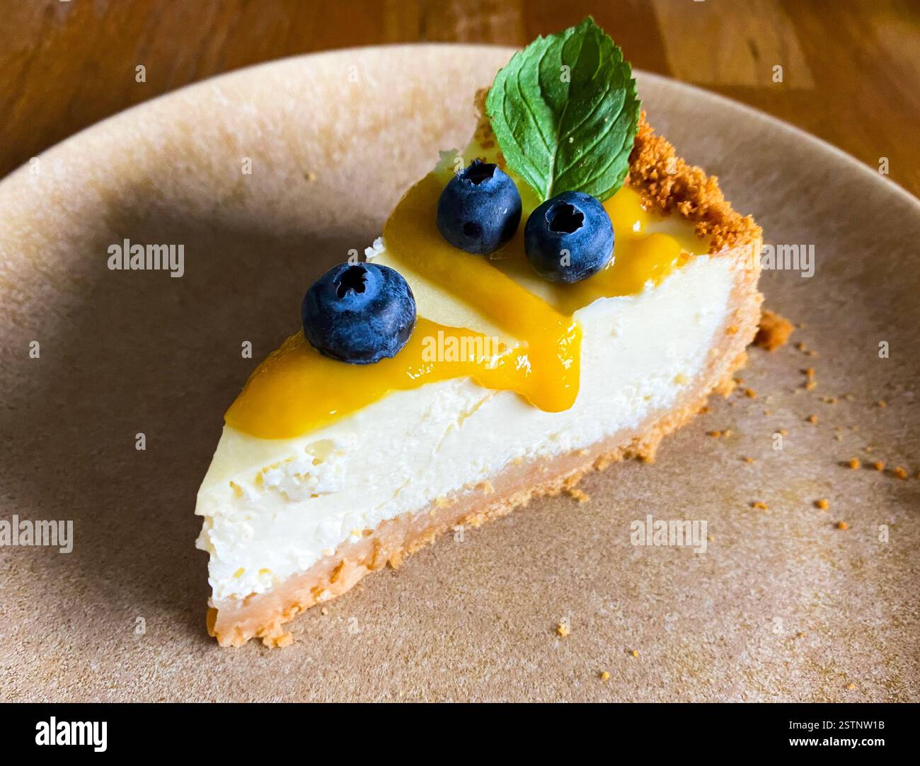 slice of cheesecake with fresh  blueberries, yellow jam and mint on the plate. side top angle  view - Smartphone Captured Stock Image