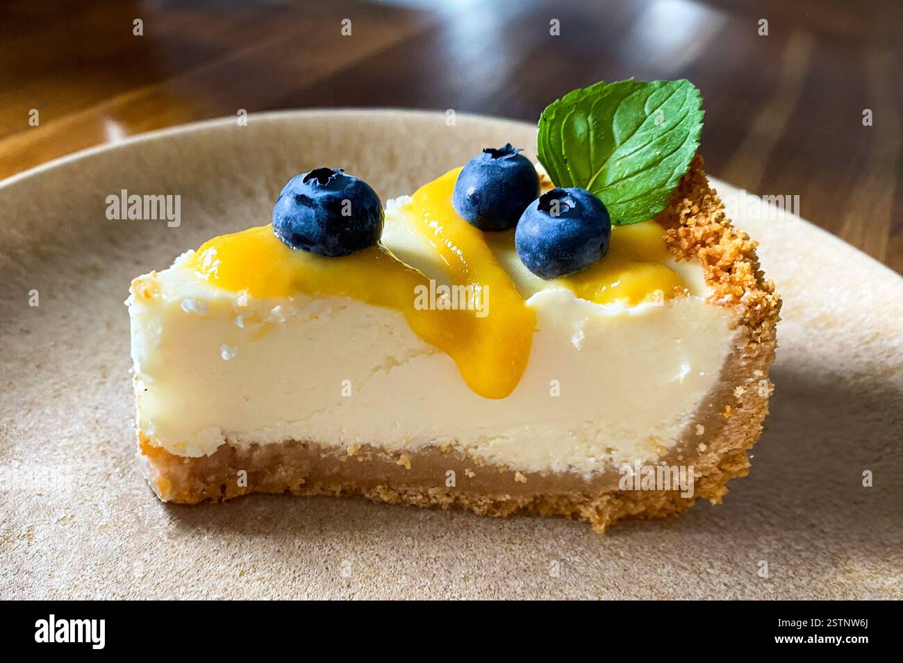 slice of cheesecake with fresh  blueberries, yellow jam and mint on the plate. side top angle  view - Smartphone Captured Stock Image
