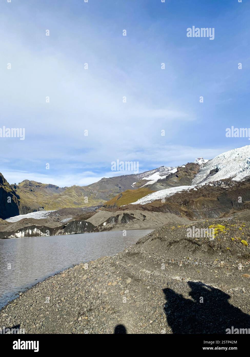 A stunning natural landscape with glacial features, rocky shoreline, and towering mountains under a clear sky Stock Photo