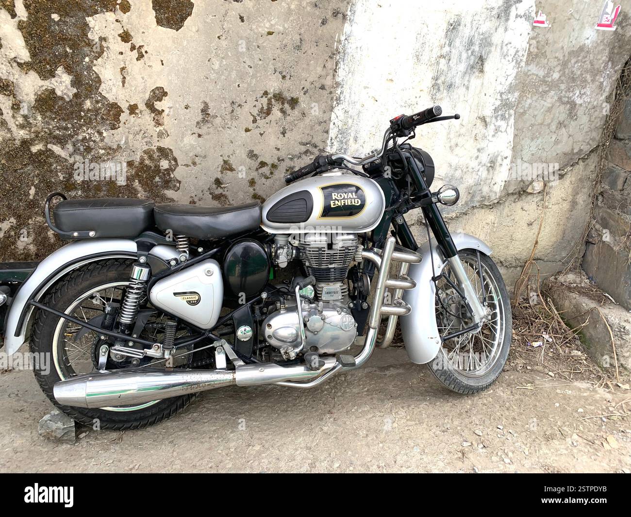 Royal Enfield Motorbike India Delhi parked new old style type wheels engine City parking style British English silver metal fast speed petrol tank - Smartphone Captured Stock Image