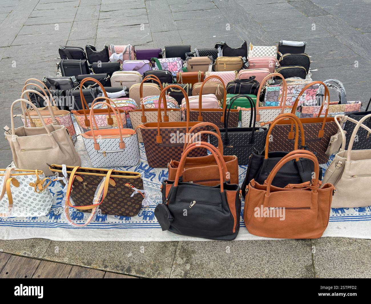 Vigo, Spain - 14 January 2025: Collection of counterfeit handbags laid out on the ground in the harbour of Vigo for sale to tourists - Smartphone Captured Stock Image