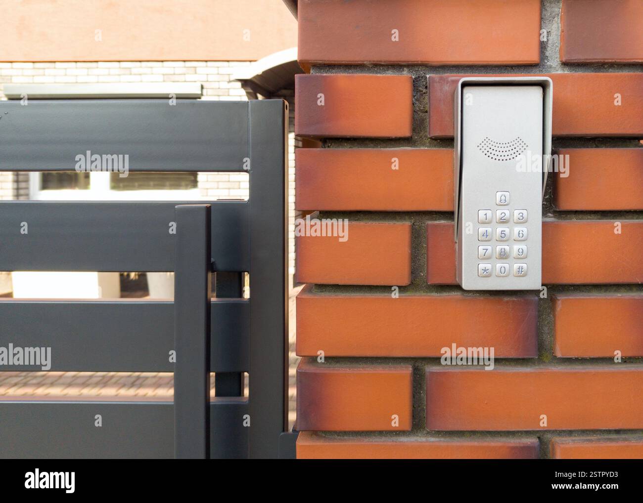 Modern Intercom Keypad on Brick Wall by Metal Gate Stock Photo