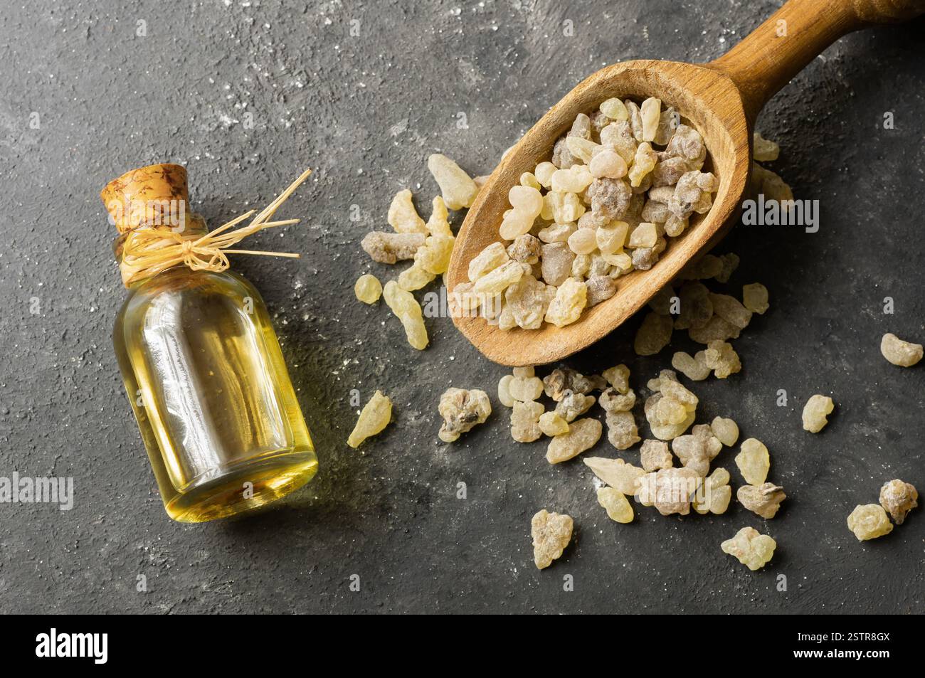 Glass bottle of frankincense essential oil with aromatic resins on rustic background, herbal medicine Stock Photo
