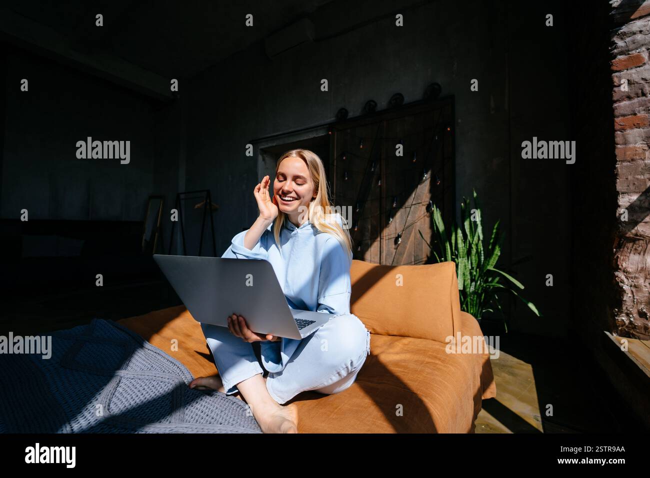 Smiling attractive woman lying on bed using laptop Stock Photo - Alamy