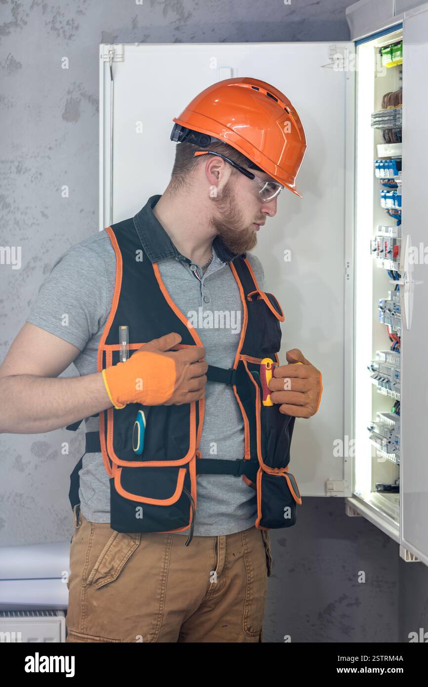 Electrician man in overalls works in the switchboard. Portrait of an electrician in overalls. Stock Photo