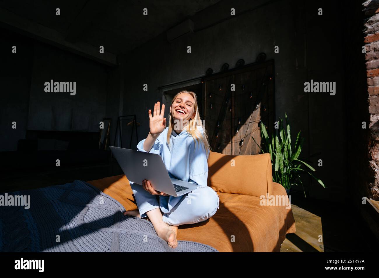 Smiling attractive woman lying on bed using laptop Stock Photo - Alamy