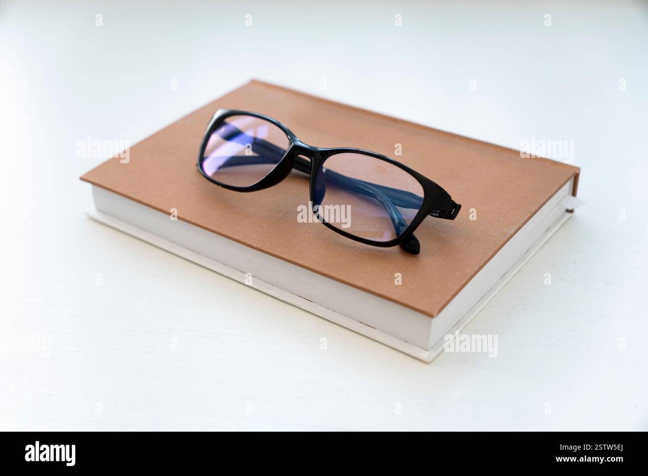 Reading glasses with books on the white table Stock Photo