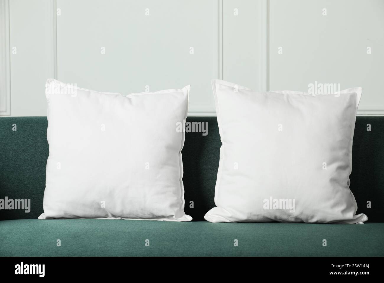 Blank soft pillows on cozy couch indoors Stock Photo