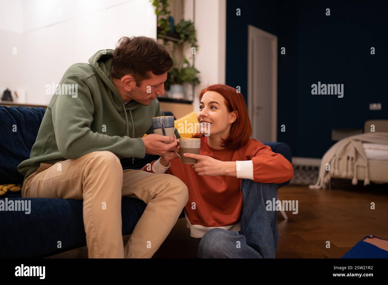 Happy couple drinking tea in cozy home atmosphere enjoying pleasant conversation Stock Photo