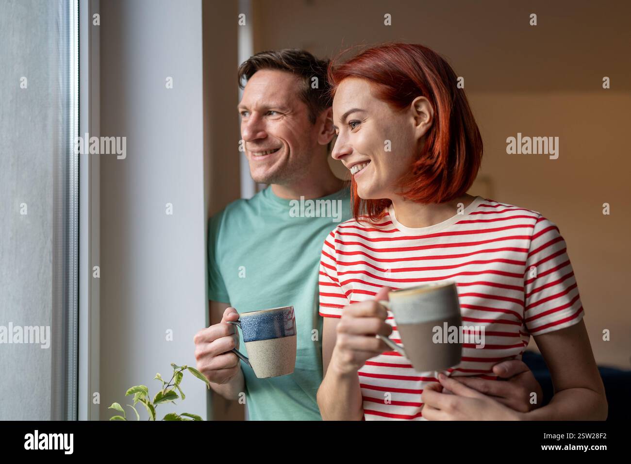Smiling happy couple drinking coffee looking out window Stock Photo