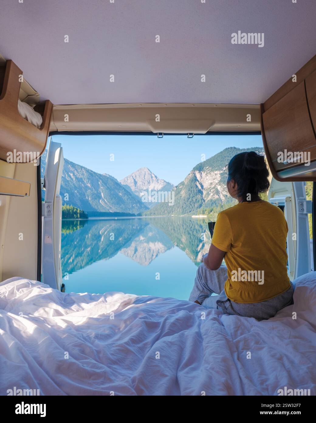 A traveler enjoys a serene morning, gazing out at the still waters of ...