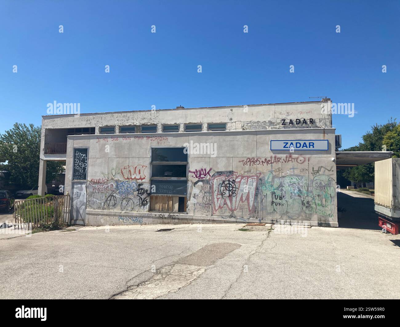 Abandoned railway station in Zadar, Croatia. Concrete building and railroad tracks with graffiti abandoned desolate ruin public transport by rail - Smartphone Captured Stock Image