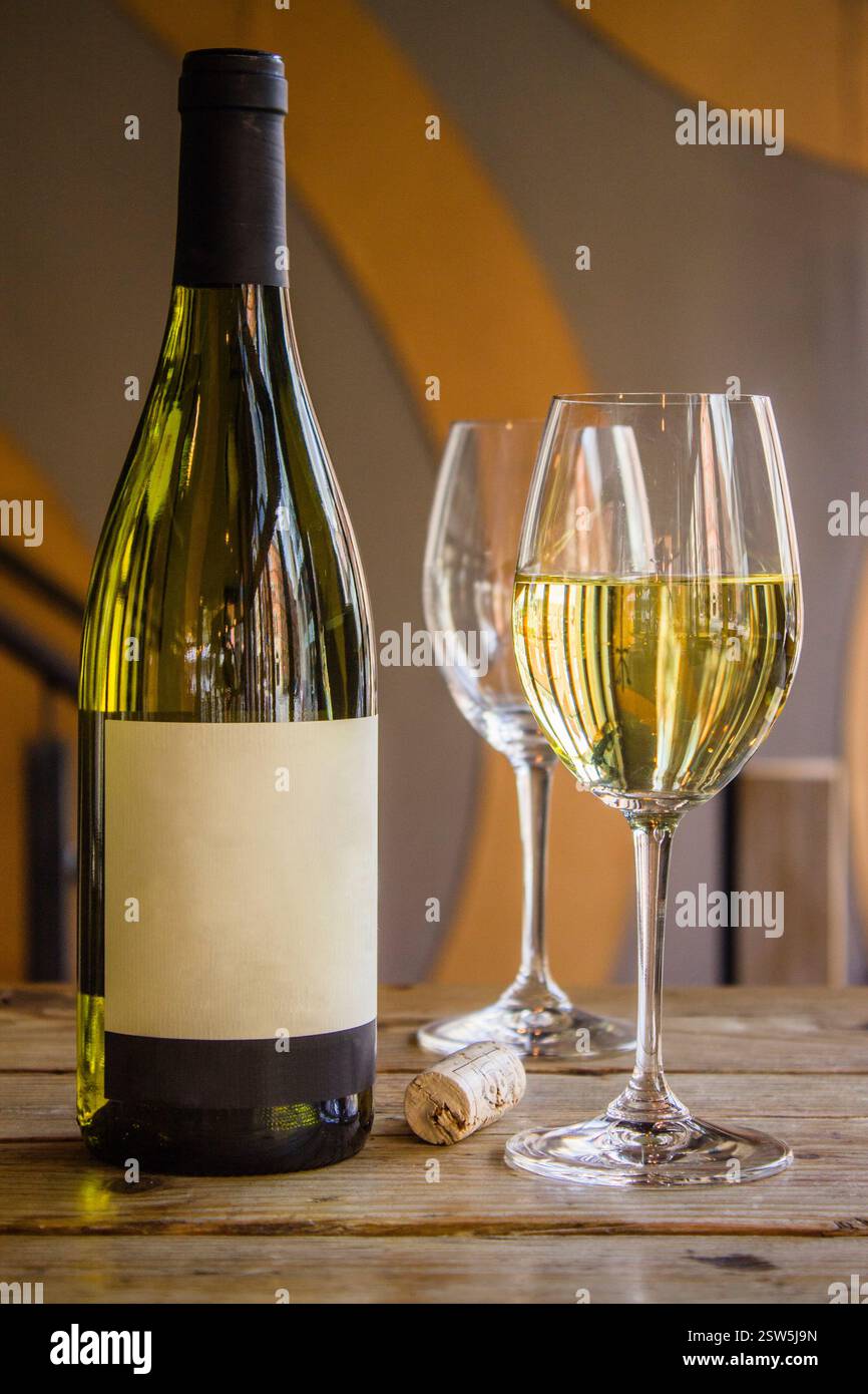 Manchester, United Kingdom, 2016: Elegant White Wine Bottle and Glasses on Rustic Wooden Table Stock Photo