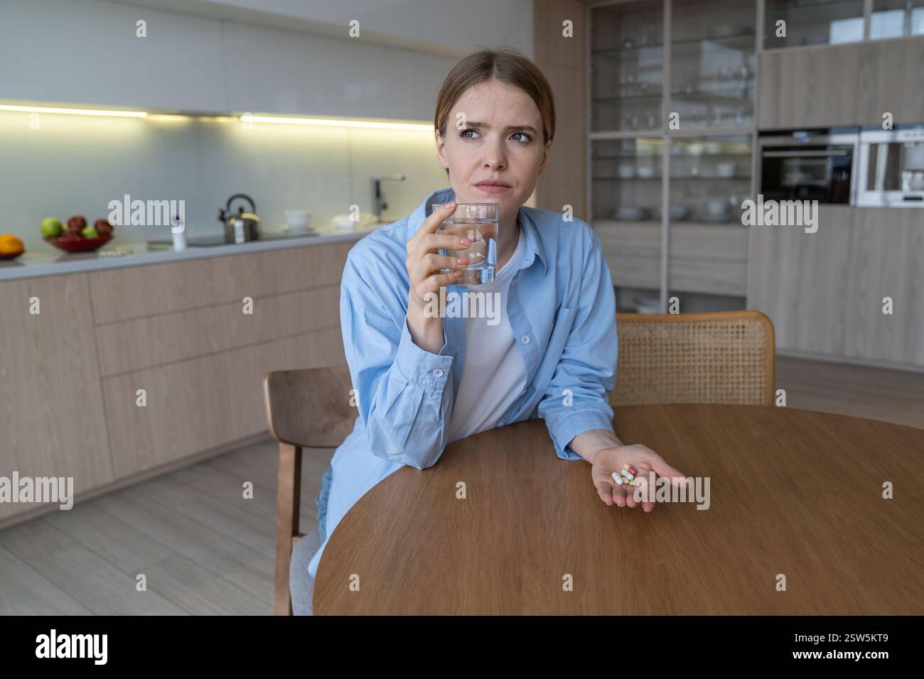 Thoughtful worried woman with stress mental health problem takes pills antidepressants try calm down Stock Photo