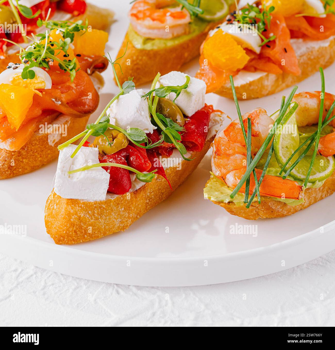 Fresh Toppings Elegant platter of assorted bruschetta with fresh toppings on a white ...