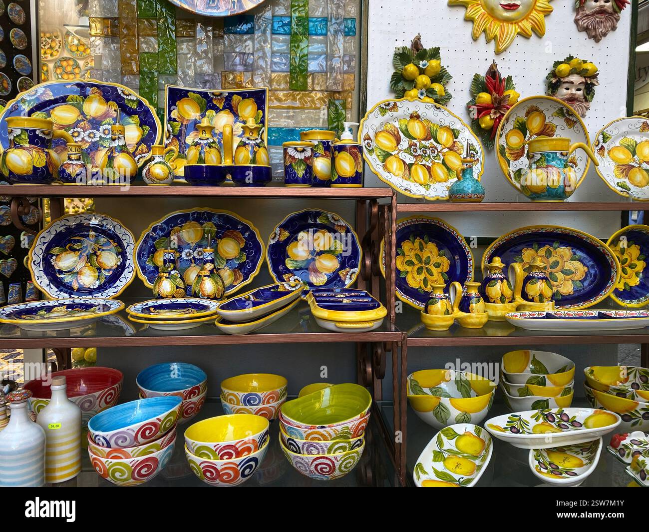 Traditional hand-painted ceramic plates, bowls, and kitchenware with vibrant lemon motifs on display in an Italian market - Smartphone Captured Stock Image