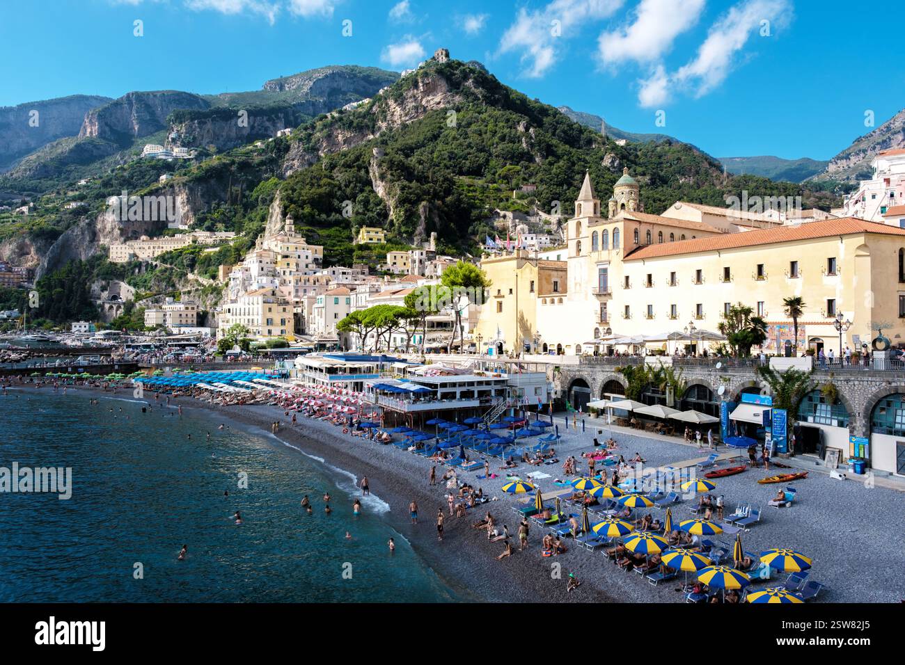 Warm sun illuminates the Amalfi Coast as tourists relax on colorful ...
