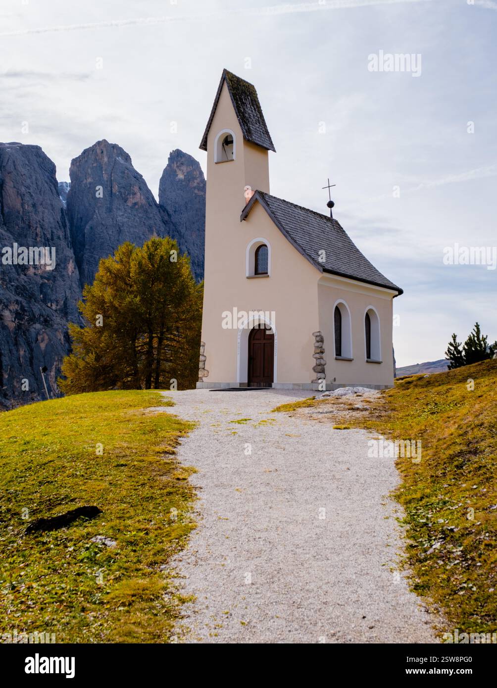 Quaint Structures A quaint chapel stands at the edge of a lush green path, surrounded by ...