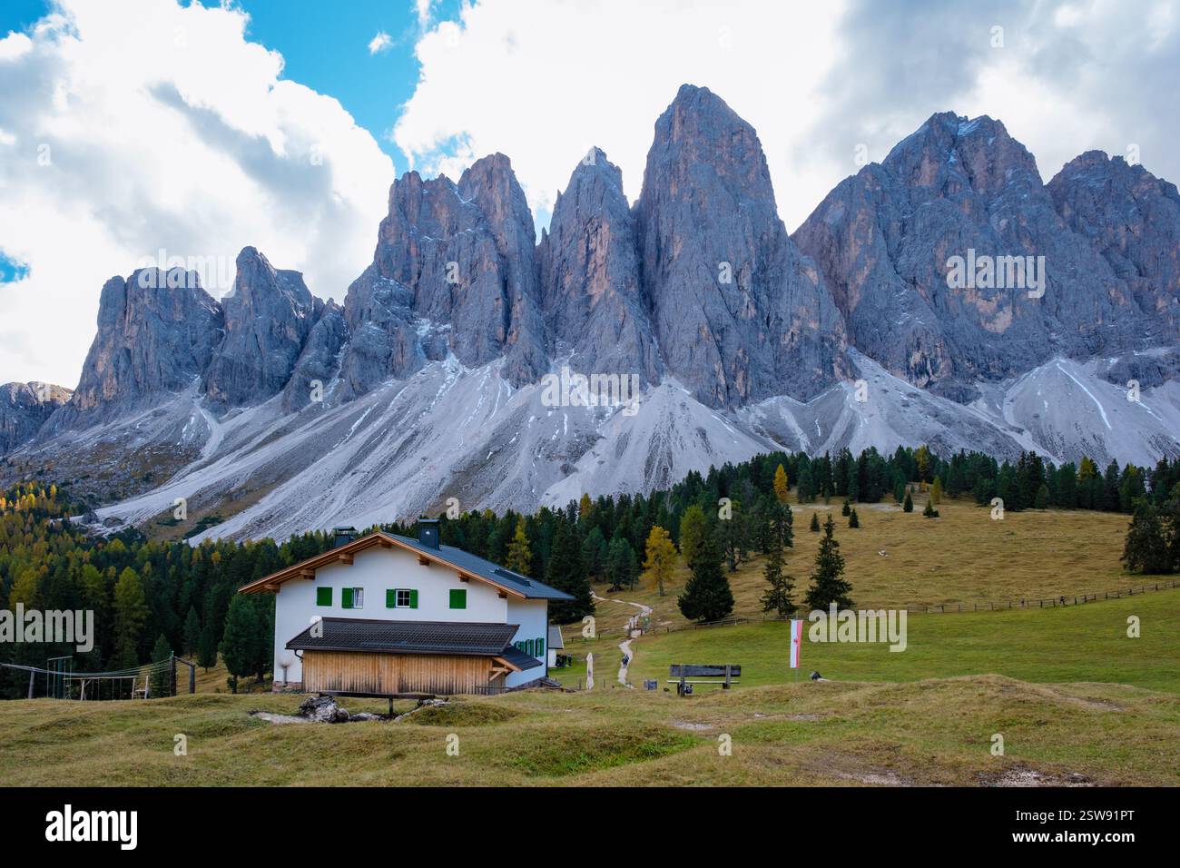 Majestic Dolomites rise above a quaint alpine house on a sunny day in ...