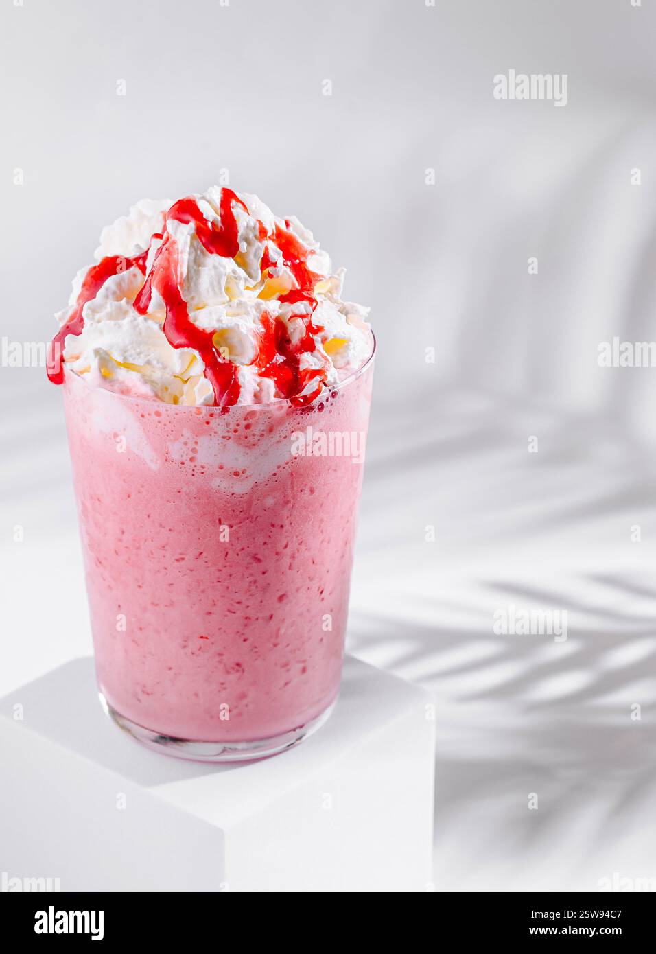 Strawberry milkshake with whipped cream and syrup standing on white ...