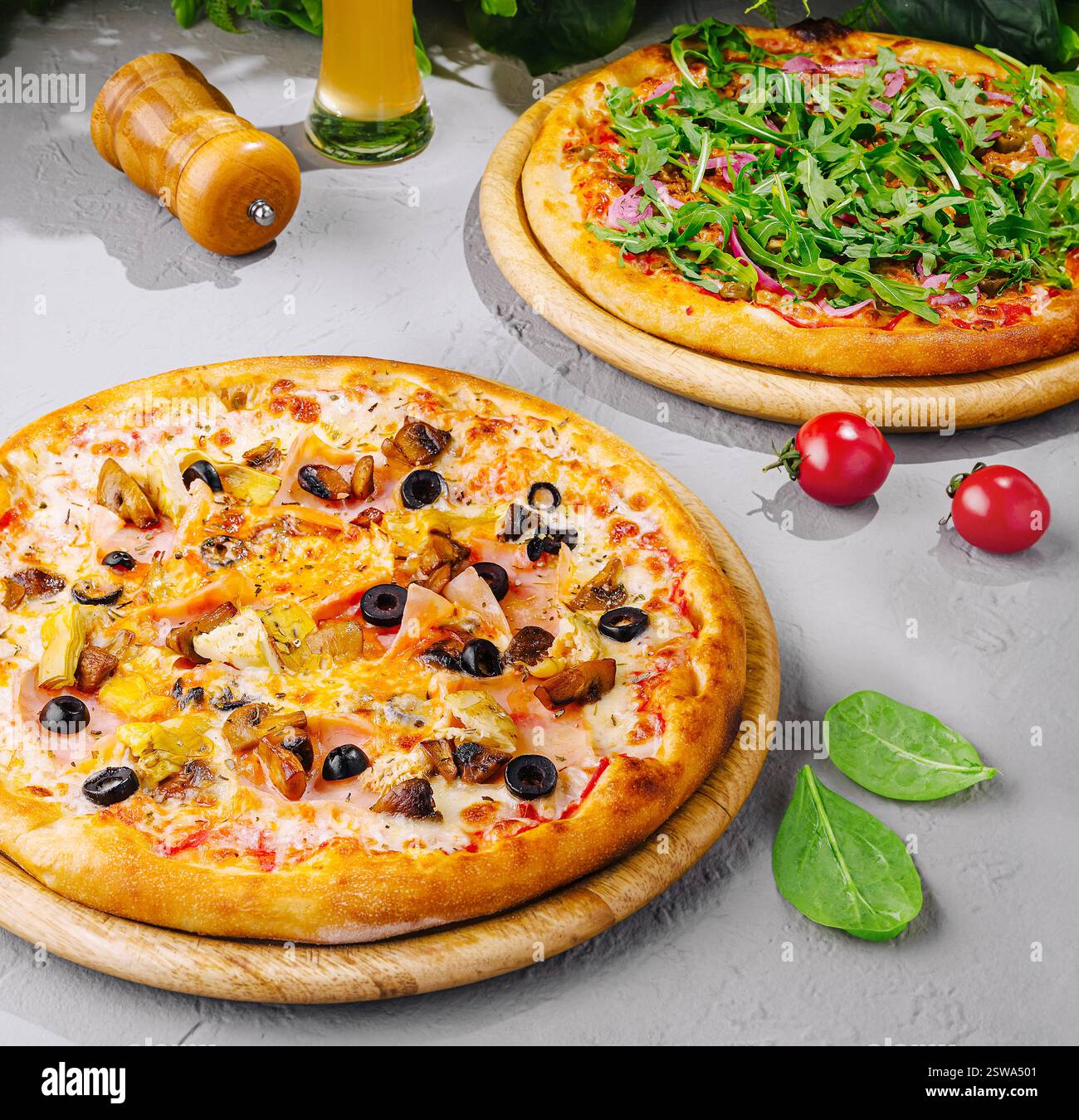 Two different pizzas with beer served on wooden boards Stock Photo