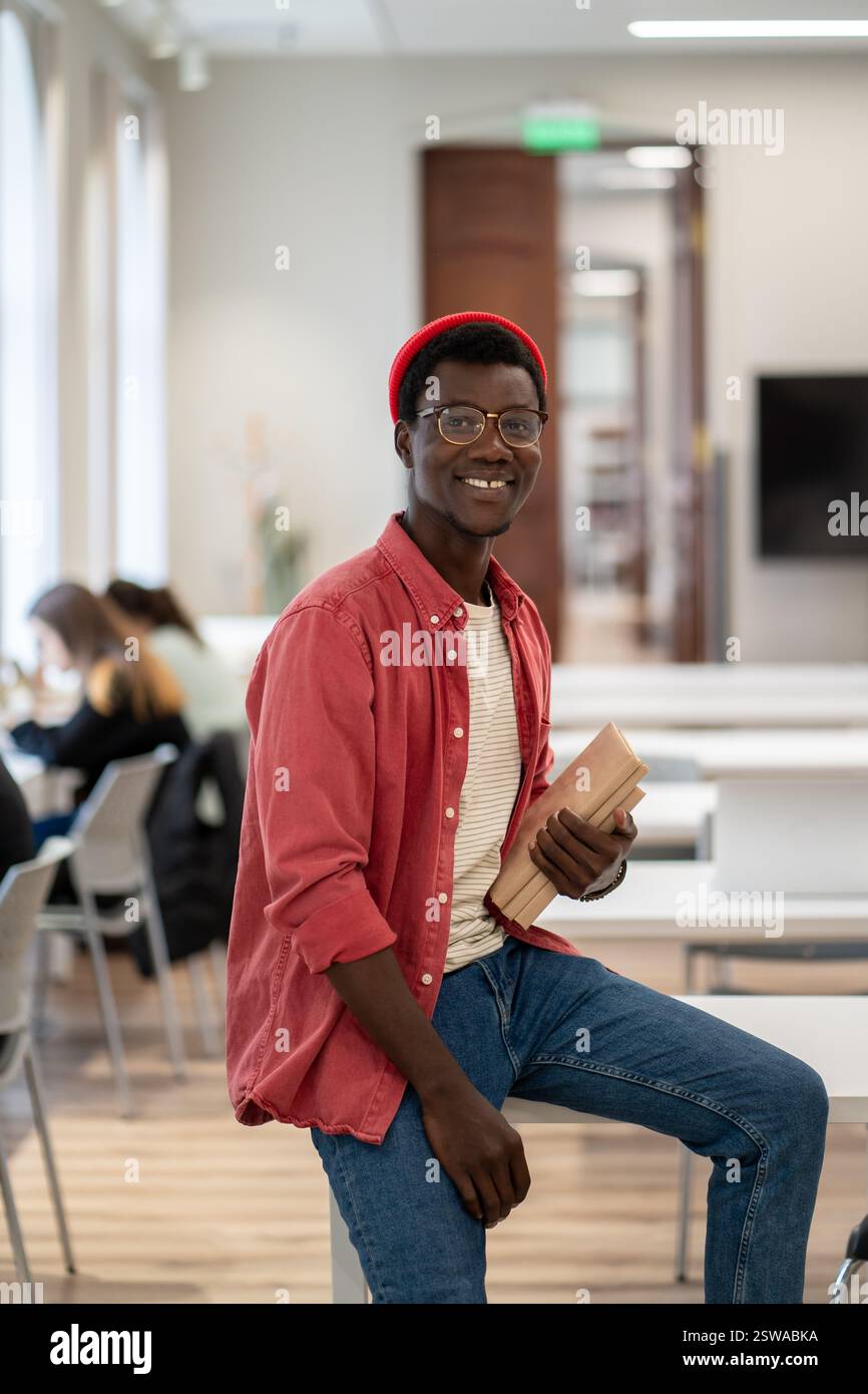 Happy smiling African guy university student in classroom or library Stock Photo