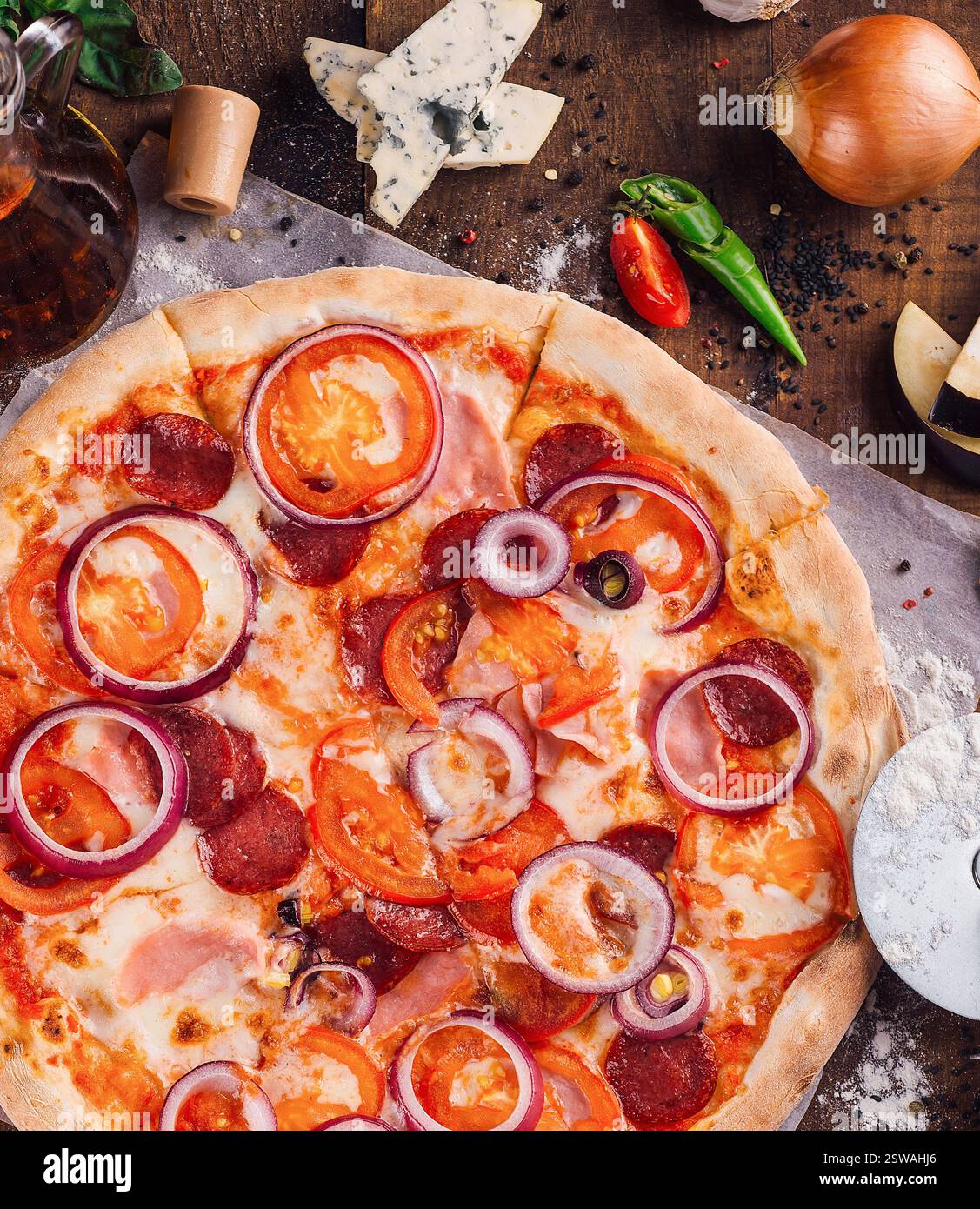 Sprade Round Delicious pizza lying on wooden table with ingredients spread around ...