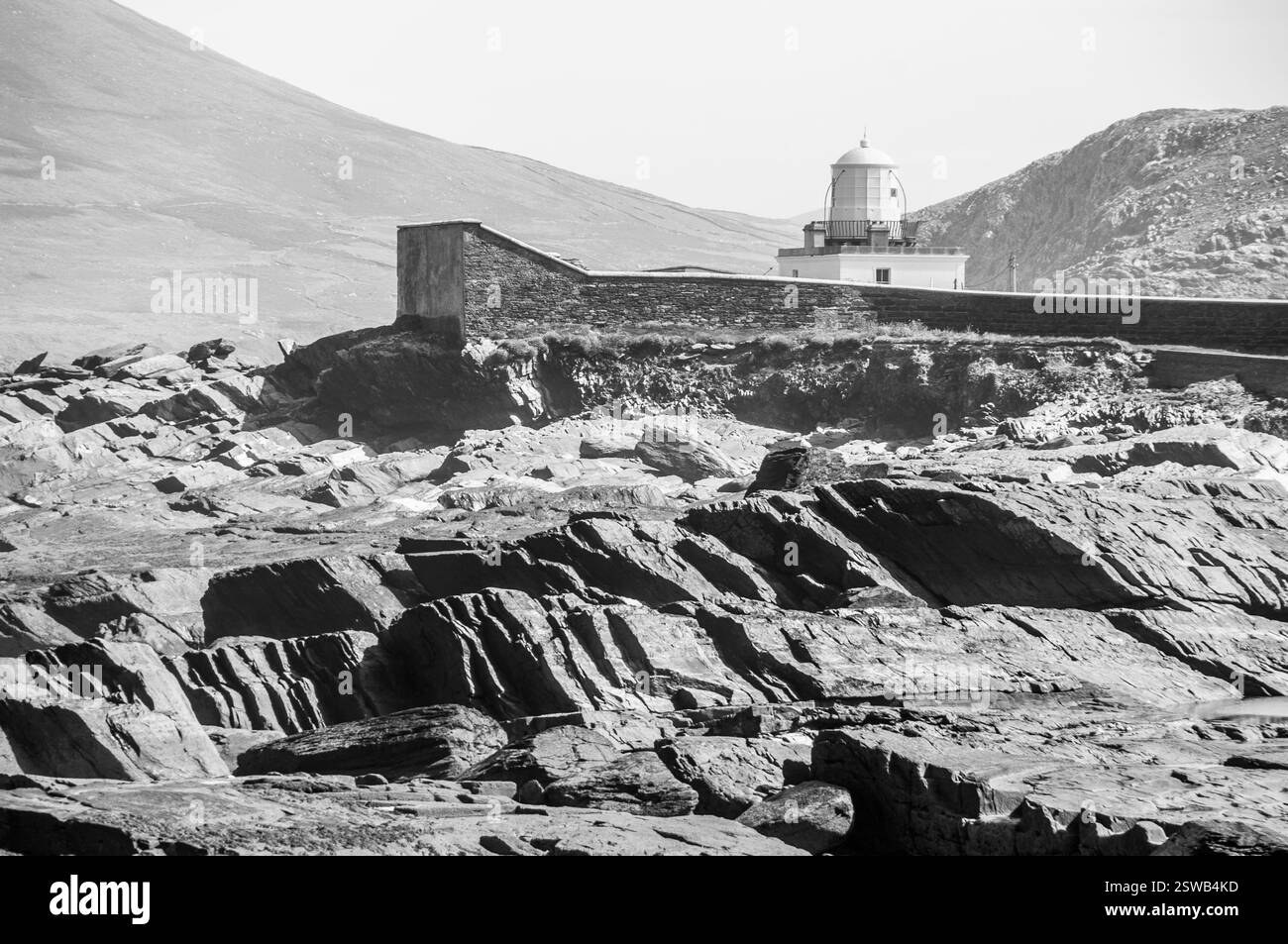 A rocky shoreline with a lighthouse in the distance. The lighthouse is ...