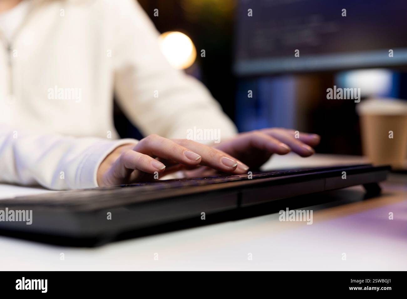 IT operator working from home developing software in JavaScript programming language using PC. Close up shot of system engineer in apartment writing lines of code on computer using keyboard Stock Photo