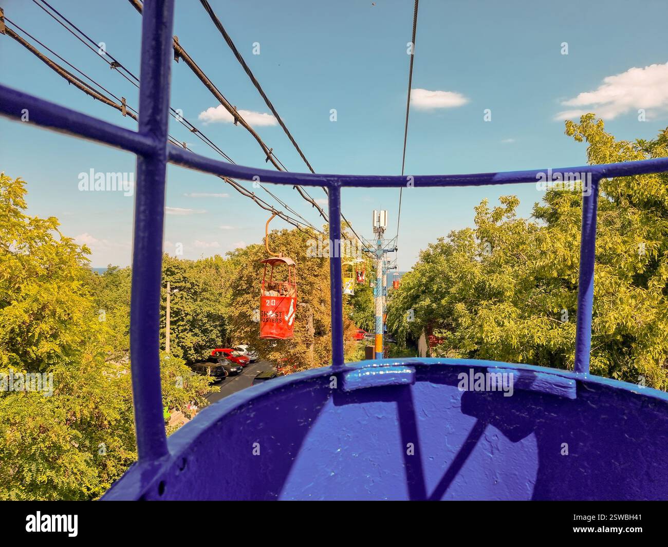 View from blue gondola of the vintage Soviet cable car in Odesa / Odessa, Ukraine to Otrada beach high above green forest trees w/ view on Black Sea - Smartphone Captured Stock Image