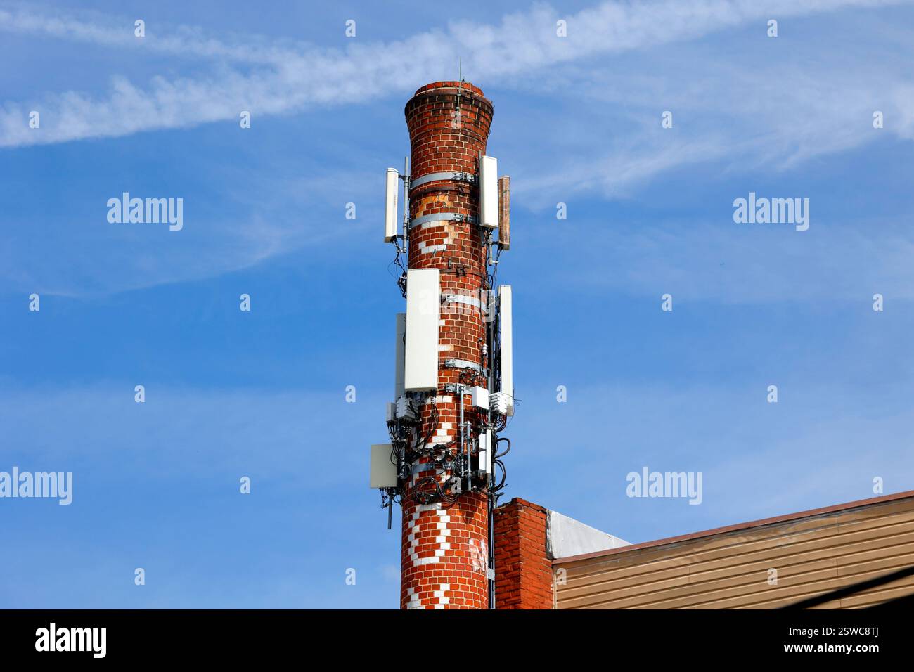 Cellphone antennas and telecom equipment attached to a decommissioned brick chimney. Stock Photo