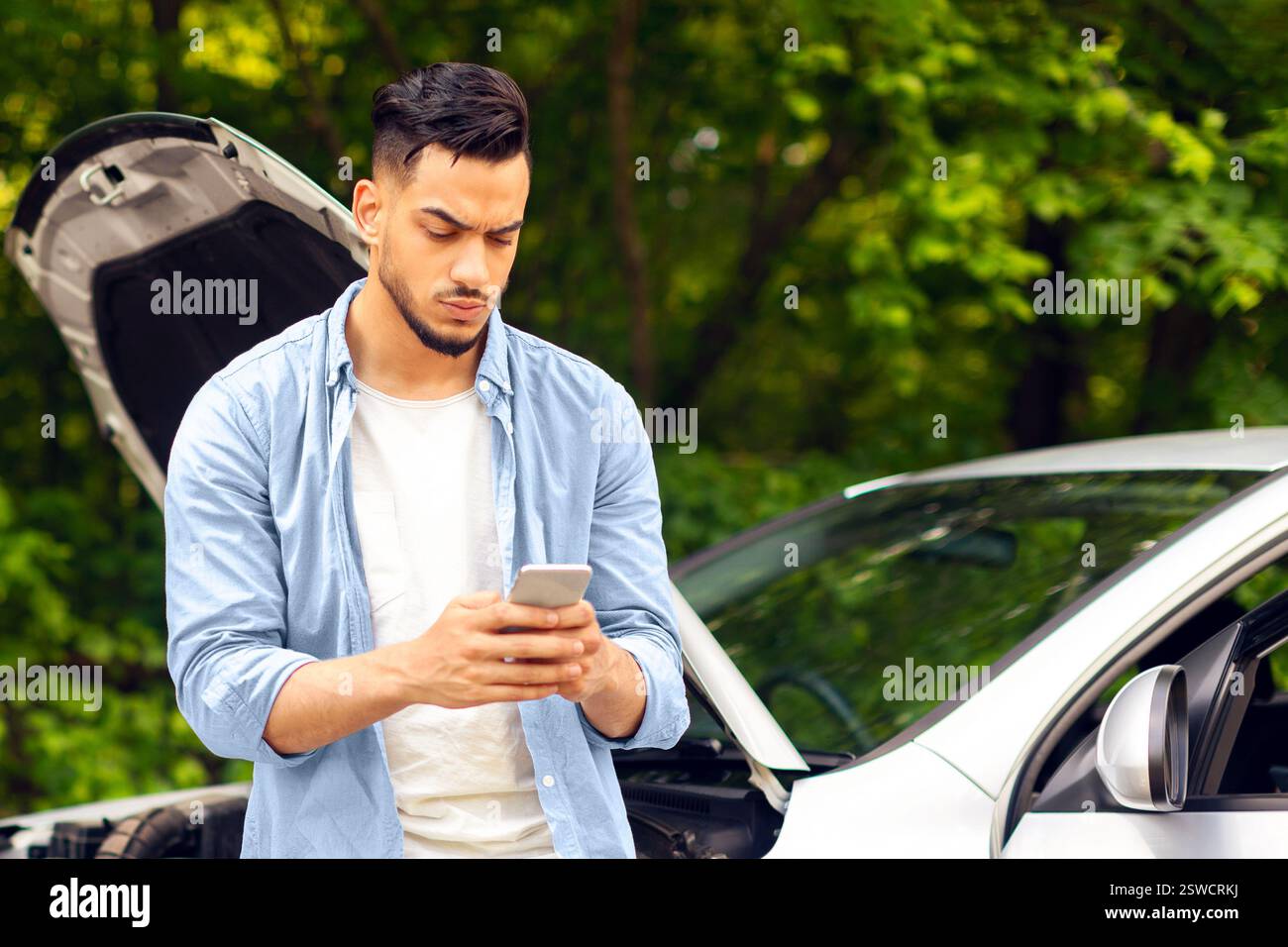 Sad arab man looking for auto service, using smartphone Stock Photo