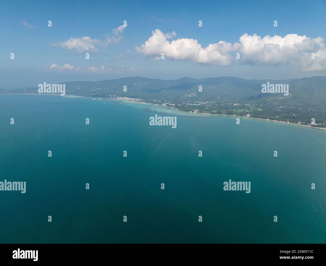 Coastal landscape with green hills and vast blue sea under clear skies ...