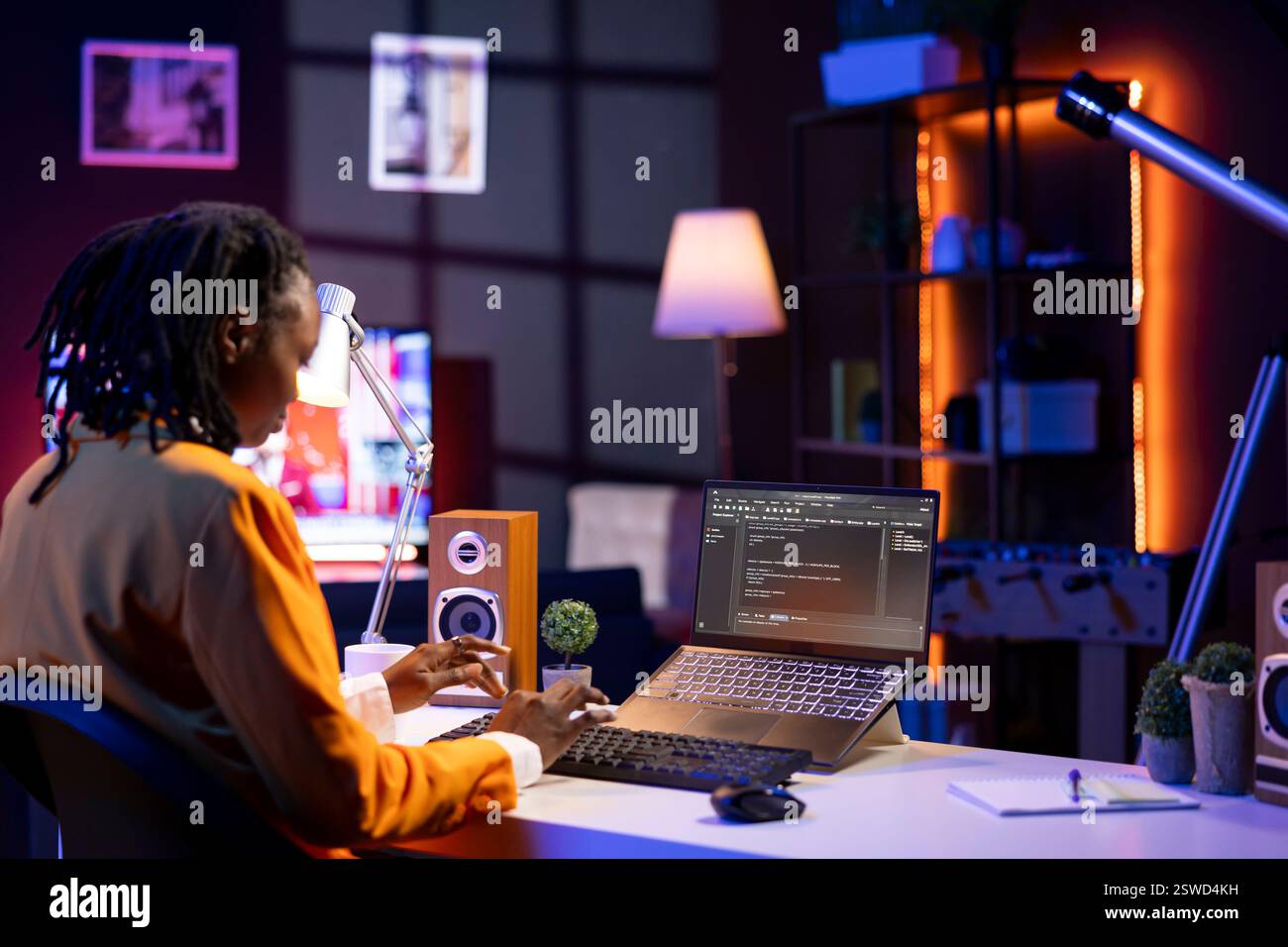 Software developer writes code on laptop screen while in apartment office using Java programming languages. Programmer remotely working on fixing database errors while working from home Stock Photo