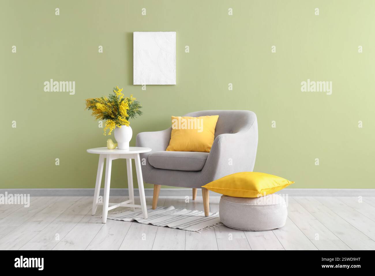 Interior of living room with armchair, table and mimosa flowers in vase ...
