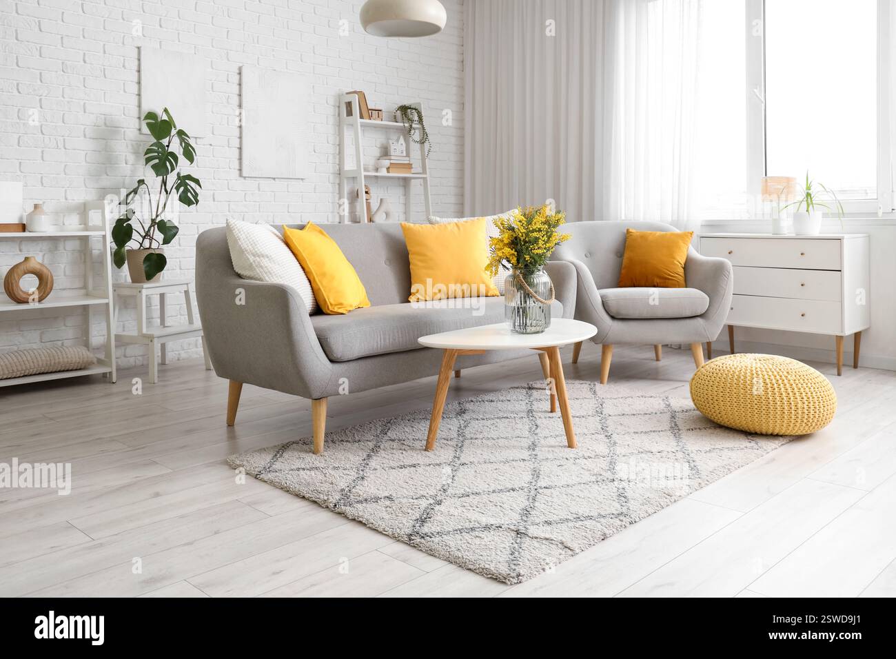 Interior of living room with sofa, armchair and mimosa flowers in vase ...