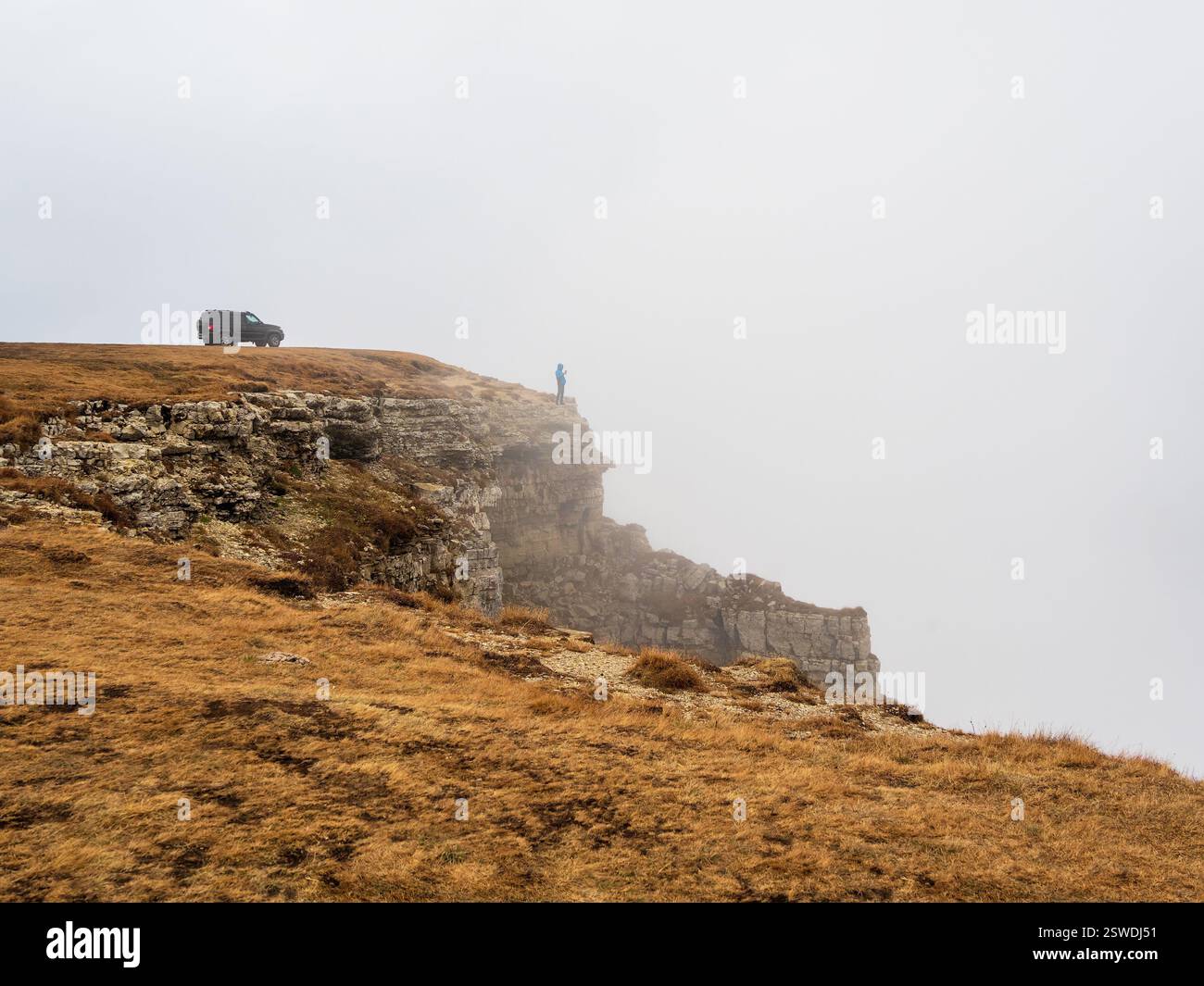 Off-road vehicle on the edge of a autumn steep cliff with dense Stock Photo