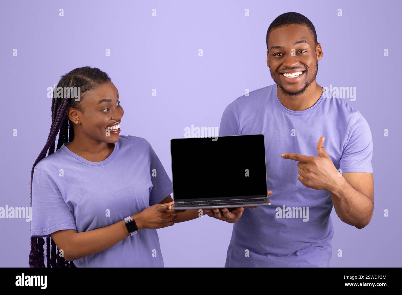 Excited black couple showing black blank laptop screen Stock Photo - Alamy