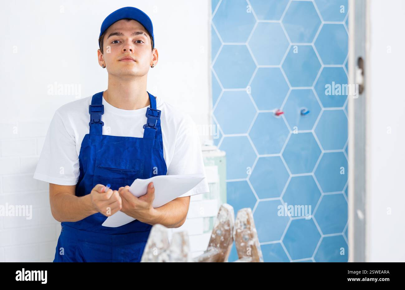 Young builder making checklist while planning indoor building overhaul Stock Photo
