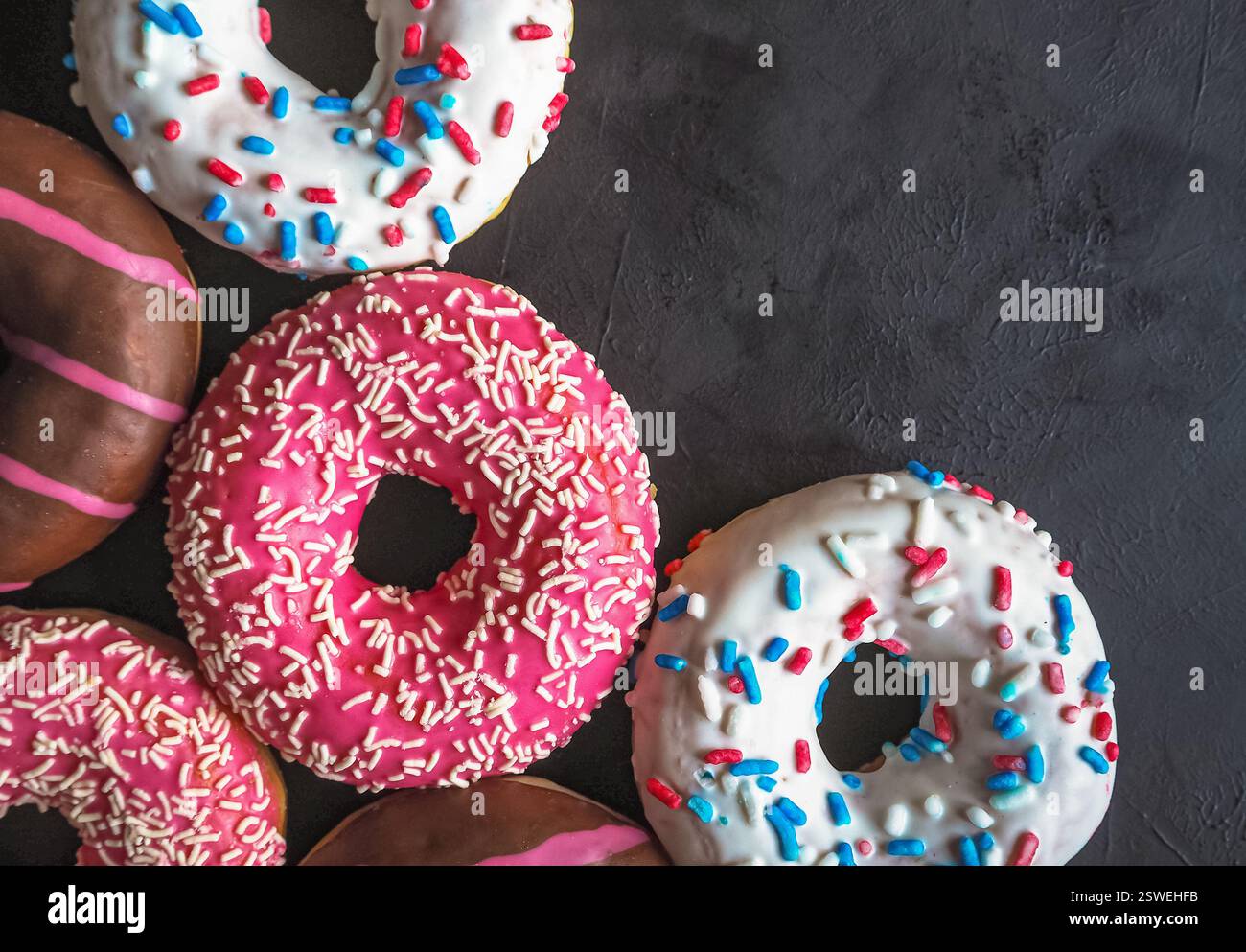 Colorful donuts on black stone table. Top view Stock Photo