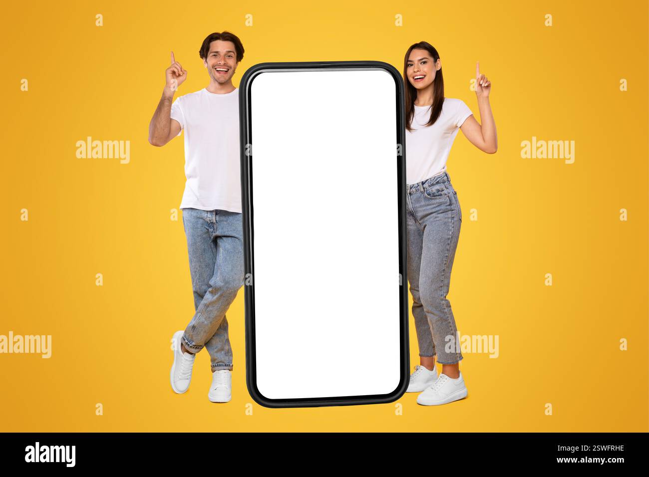 Couple standing next to big white empty smartphone screen Stock Photo
