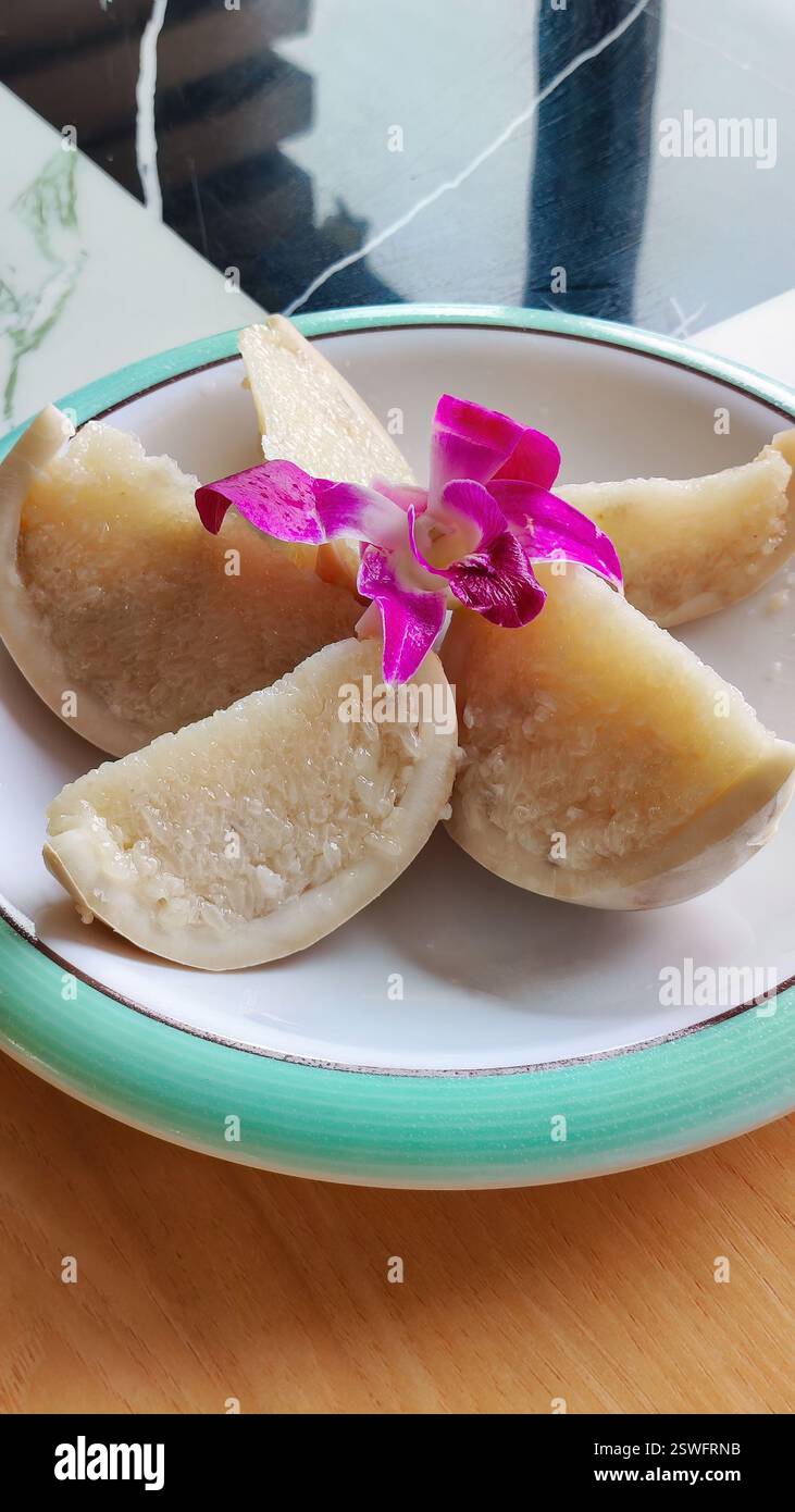 Coconut rice is a local specialty dessert of Hainan, which is also called 'coconut boat'. Coconut shell with glutinous rice and dried coconut flakes Stock Photo